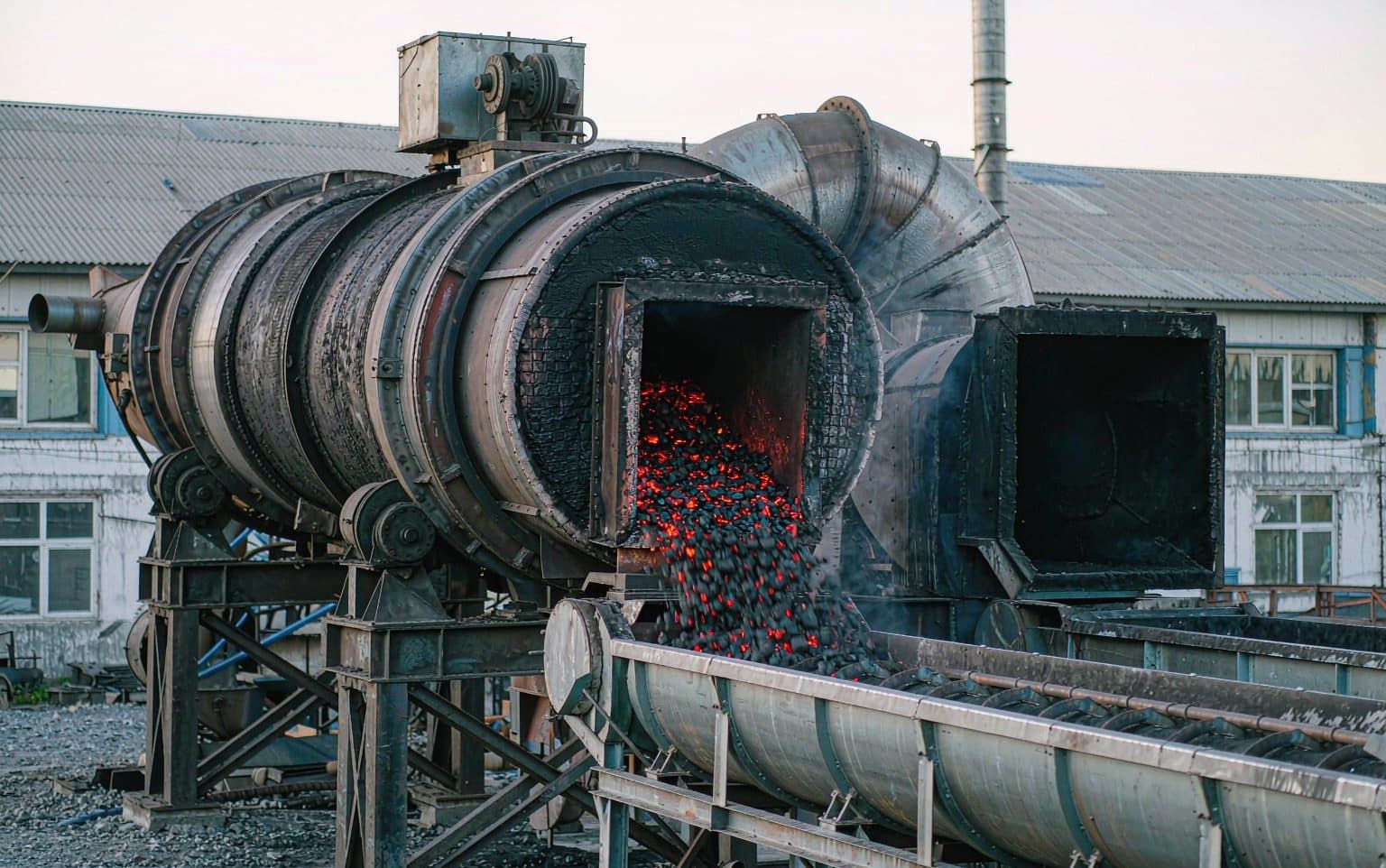 Rotary carbonization kiln discharging hot char into a water-cooled conveyor